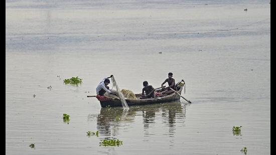 Fishermen try to catch fish from the Ganga river as the water level rises in Prayagraj on Monday (PTI)