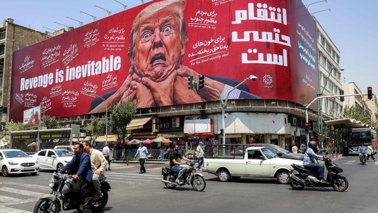 Motorists drive past a large billboard pledging revenge against US President Donald Trump along Jomhouri Street in central Tehran on July 27, 2026. Iran's foreign ministry said on July 27 that the US was not involved in recent talks with Oman over the administration of the strategic Strait of Hormuz. Traffic through the vital global shipping route has largely been under Iranian control since the outbreak of war with Israel and the United States on February 28. 