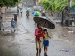 A man with a child makes his way amid heavy monsoon rain, in New Delhi, Tuesday, July 28, 2026. Parts of Delhi received rain with the India Meteorological Department (IMD) issuing an 'orange' alert for more rain at several places over the next few hours.