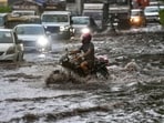Vehicles move through a waterlogged road amid heavy rain. 