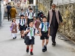 Students walk towards their school on the first day of classes after a 21-day summer break in Srinagar on Monday. (ANI)