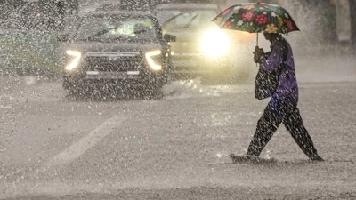 A person crosses a road amid rainfall, in New Delhi. (PTI) A person crosses a road amid rainfall, in New Delhi. (PTI)