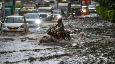 Vehicles move through a waterlogged road amid heavy rain. (PTI)