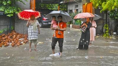 People wade through a waterlogged road in Mayur Vihar Phase 2 on Tuesday. ((Sanjeev Verma/HT Photo))