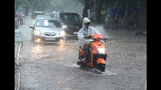 Commuters on their way during rain and waterlogging at Aroma Light Point in Chandigarh on Tuesday. (Keshav Singh/HT)