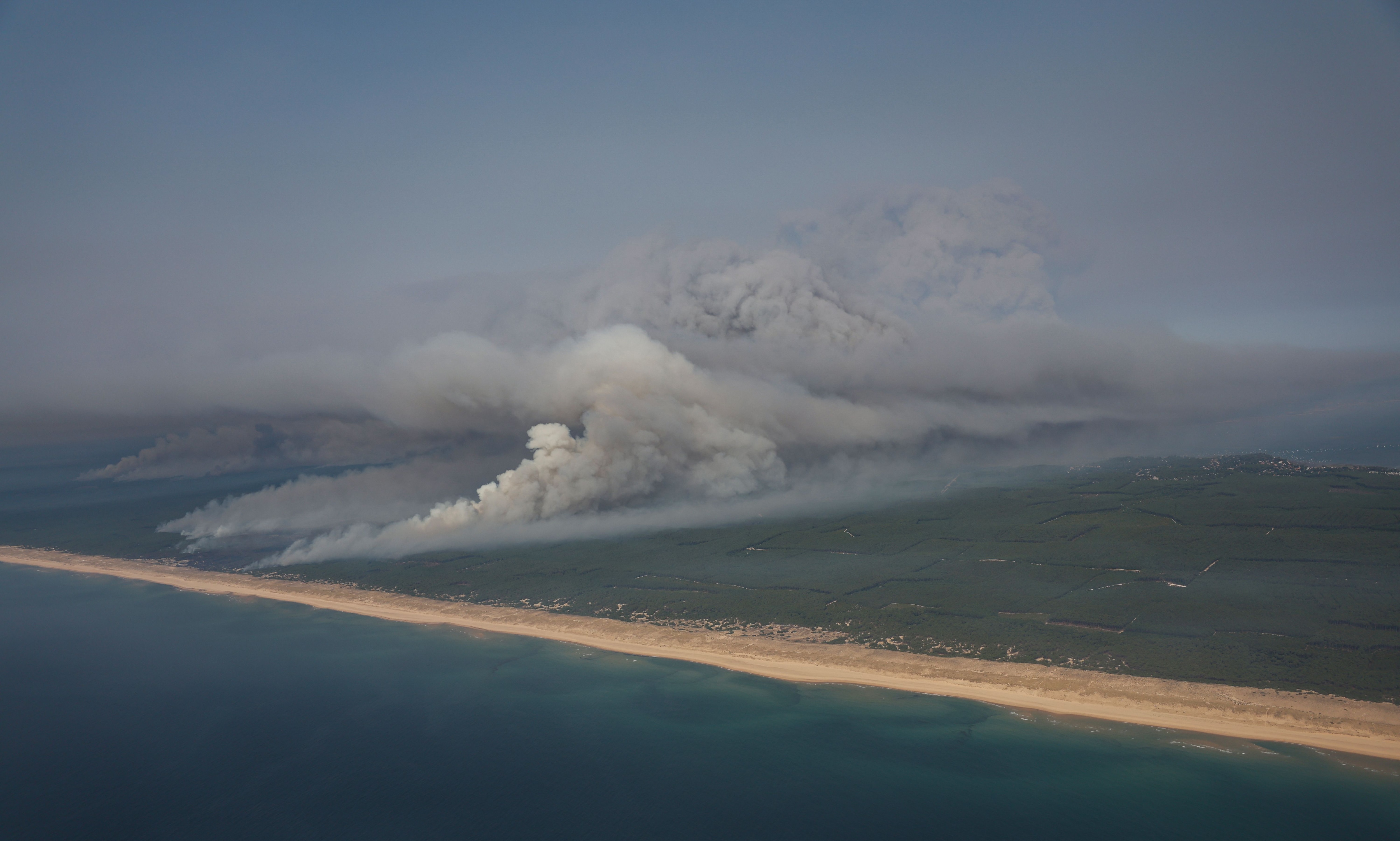 Smoke emanating from the wildfire north of the Arcachon basin covering the forest, with a view of a beach and the Atlantic Ocean near Lege-Cap-Ferret, southwestern France, (AFP)