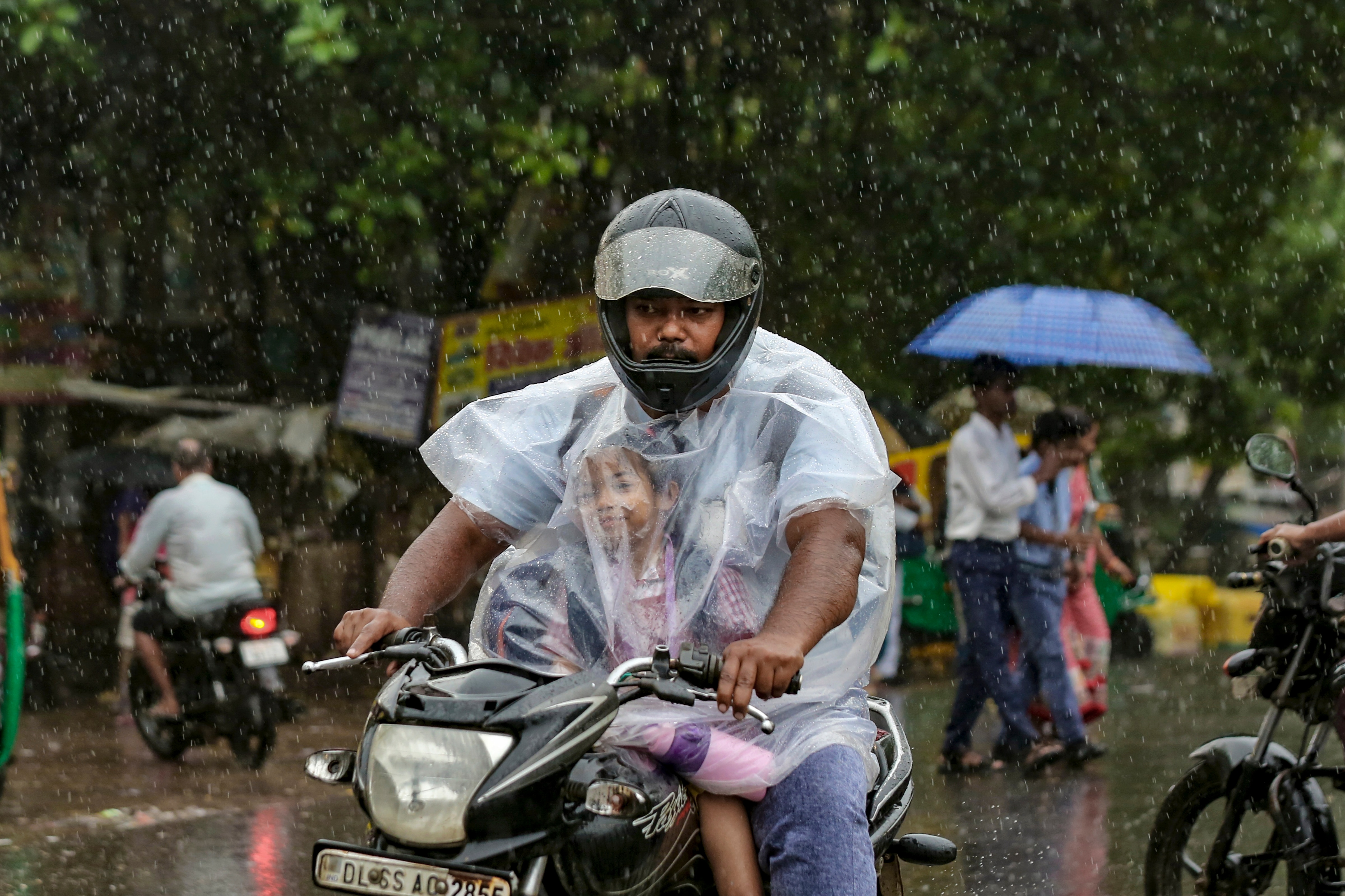 A commuter with a child makes his way amid heavy monsoon rain, in New Delhi, Tuesday, July 28, 2026. (PTI) A commuter with a child makes his way amid heavy monsoon rain, in New Delhi, Tuesday, July 28, 2026. (PTI)