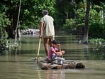 A girl and her grandfather travel on a raft through floodwaters following heavy monsoon rains at a village in Assam's Sivasagar district. (AFP)