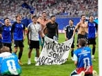 Argentina's Giovani Lo Celso, right, holds a banner with the words "The Malvinas are Argentine", referring to the Falkland Islands, at the end of the World Cup semifinal