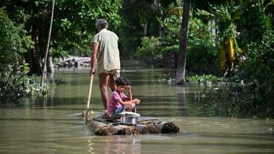 A girl and her grandfather travel on a raft through floodwaters following heavy monsoon rains at a village in Assam's Sivasagar district. (AFP)