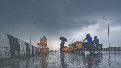 People out in the rain near Akshardham Temple on Wednesday. (RAJ K RAJ /HT PHOTO)