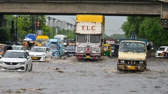 Vehicles wade through a waterlogged stretch during rain. (Parveen Kumar/HT)