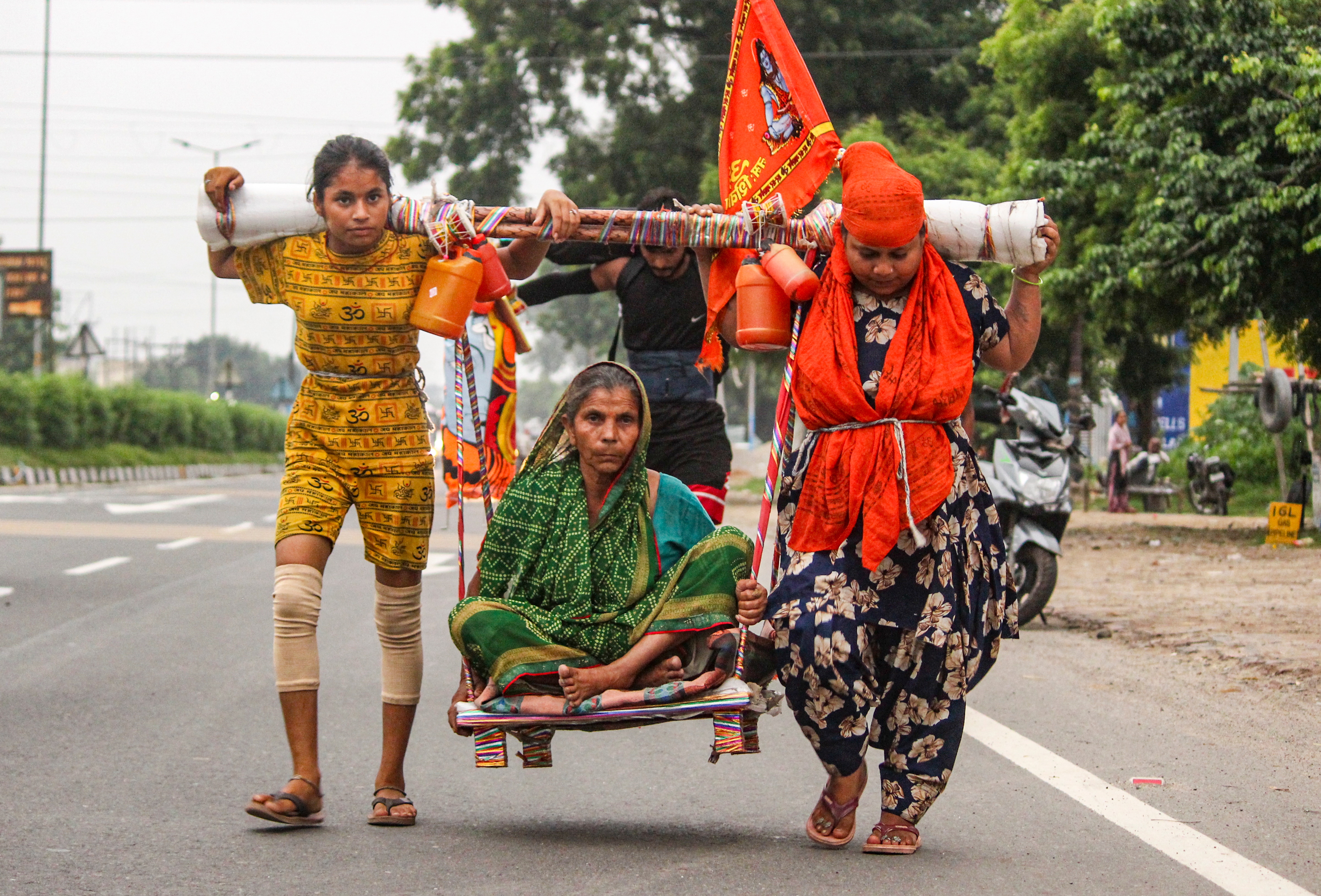 Devotee Aarti, right, carries her mother-in-law, Usha, on a shoulder-borne seat as they return after collecting holy Ganga water from Haridwar during the Kanwar Yatra, in Meerut. (PTI)
