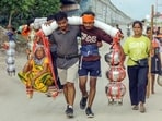 Brothers carry their grandmother in a traditional kanwar while carrying holy water to Noida from Haridwar.