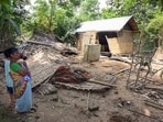 A woman with kids looks her damaged house after devastating floods at Sonari, in Charaideo on Sunday. 