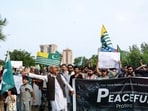 People chant slogans and hold placards, flags, and a banner in support of peaceful protesters in Pakistan-occupied Kashmir, during a demonstration in Islamabad, Pakistan.