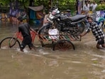 Residents use a three-wheeled cart to transport a motorcycle through a waterlogged road following heavy rainfall, in Surat, Gujarat.