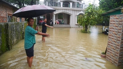 Locals show the accumulated water on the road caused by rainfall, in Dehradun on Tuesday. (ANI Photo)