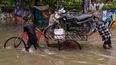 Residents use a three-wheeled cart to transport a motorcycle through a waterlogged road following heavy rainfall, in Surat, Gujarat. (PTI Photo) Residents use a three-wheeled cart to transport a motorcycle through a waterlogged road following heavy rainfall, in Surat, Gujarat. (PTI Photo)