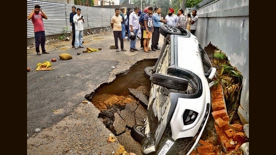 A car in a sinkhole at Gurdev Chowk after the carriageway caved in during rain in Ludhiana on Thursday morning. The driver had a narrow escape and the car was later pulled out using a crane. (Gurpret Singh/HT)