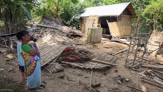 A woman with kids looks her damaged house after devastating floods at Sonari, in Charaideo on Sunday.