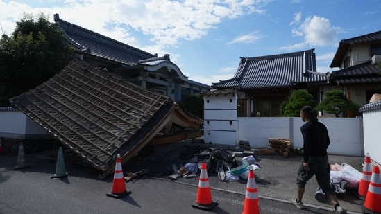 A man helps clean the damaged gate of Jofukuji Buddhist temple in Kumamoto, southwestern Japan, Wednesday, July 29, 2026, the day after an earthquake hit the area. (AP Photo/Hiro Komae)