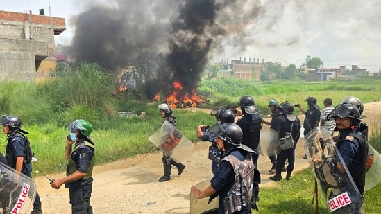 Members of Nepal Police stand next to burnt motorbikes as they wait for a fire engine during a clash between two communities in Siraha, Nepal.