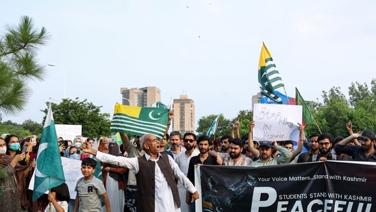 People chant slogans and hold placards, flags, and a banner in support of peaceful protesters in Pakistan-occupied Kashmir, during a demonstration in Islamabad, Pakistan.