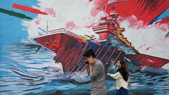 People walk past a mural depicting a U.S. aircraft carrier under missile attack in downtown Tehran, Iran, Sunday, May 17 (AP Photo/Vahid Salemi)