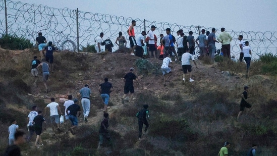 People gather on a hilltop near Bab Sebta on the Morocco-Spain border, near Spain's enclave of Ceuta and the Moroccan town of Fnideq on July 30, 2026. (Photo by Abdelmajid BZIOUAT / AFP)