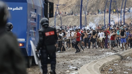 Moroccan security forces clash with migrants attempting to cross into Spain's North African enclave of Ceuta near the town of Fnideq, on the Morocco-Spain border, on July 31.
