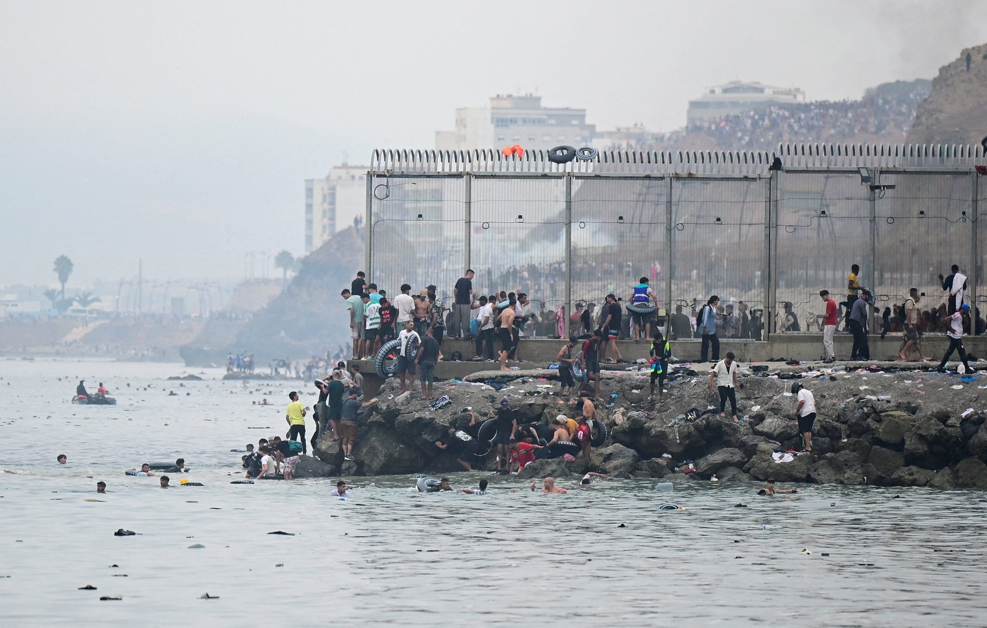 Migrants gather by the border fence as they cross the Spanish border, swimming through the sea, as seen from Ceuta, Spain, (Reuters)
