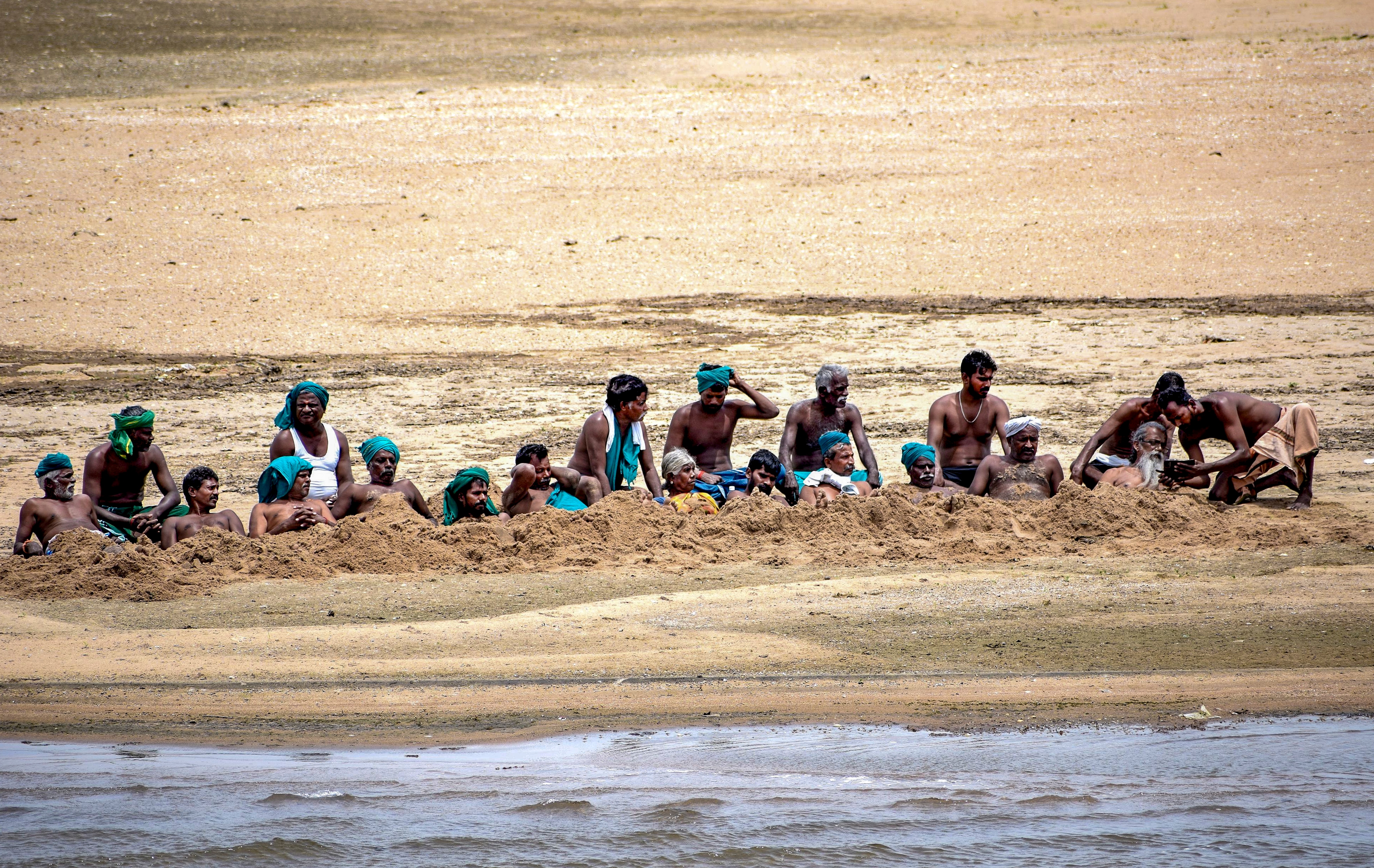 Farmers bury themselves in the sand on the Cauvery riverbed to protest, in Tiruchirappalli district of Tamil Nadu. (PTI) Farmers bury themselves in the sand on the Cauvery riverbed to protest, in Tiruchirappalli district of Tamil Nadu. (PTI)