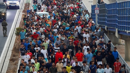Police officers and Spanish soldiers escort a big group of migrants to the border to take them out of Spain, after mass crossings of migrants on foot and by sea from Morocco into Spanish territory, in Ceuta, Spain, August 1, 2026.