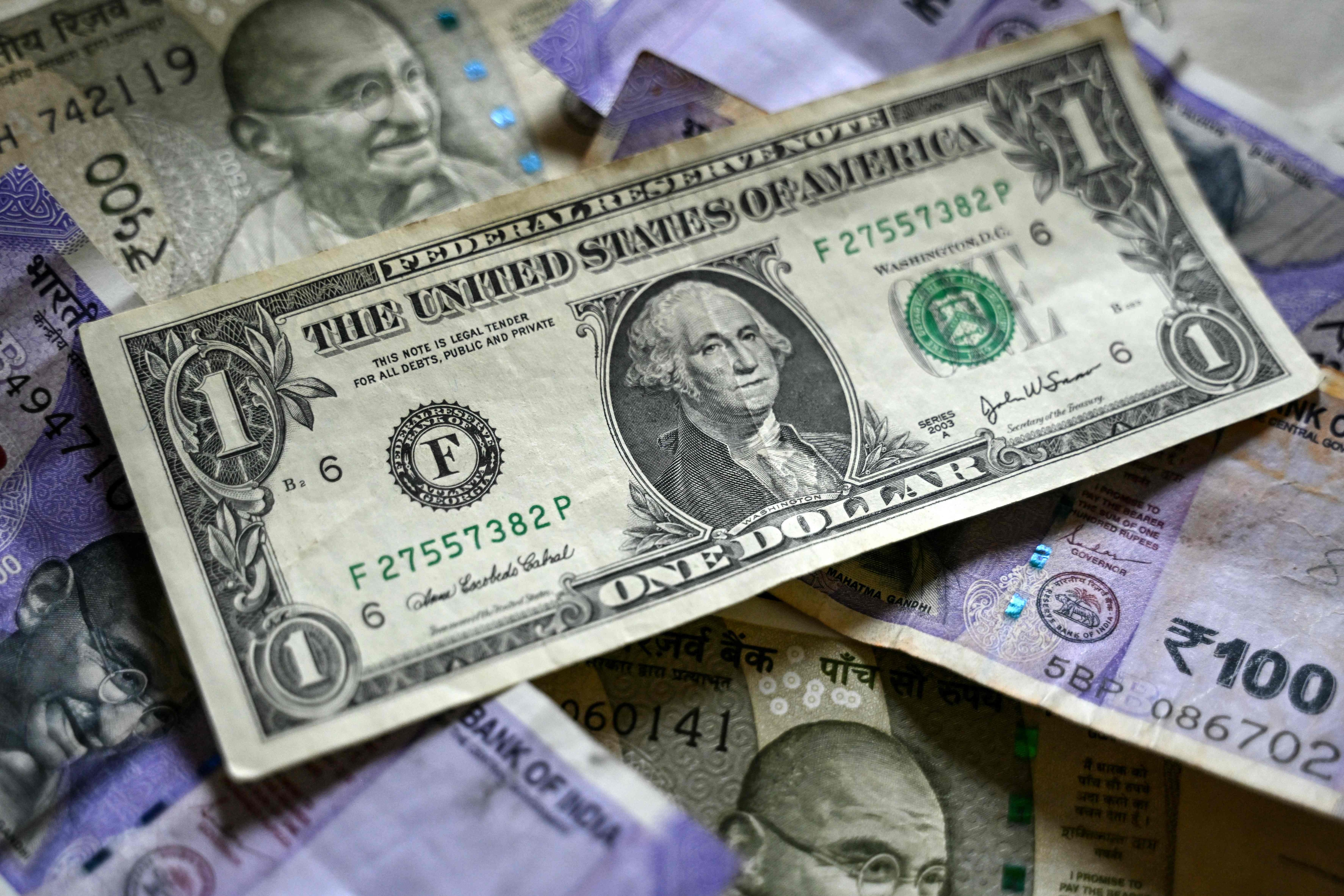 This photo illustration shows a US dollar banknote placed over Indian rupee banknotes in Bengaluru. (AFP) This photo illustration shows a US dollar banknote placed over Indian rupee banknotes in Bengaluru. (AFP)