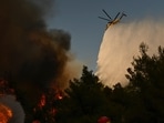 A firefighting helicopter drops water over a smoke-filled forest during a wildfire near Porto Germeno, northwest of Athens, Greece, Sunday, Aug. 2, 2026. (AP Photo/Michael Varaklas)