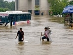 Ahmedabad: People wade through floodwater while a bus lies partially submerged following heavy monsoon rainfall, on the outskirts of Ahmedabad, Gujarat, Saturday, July 25, 2026.(PTI)