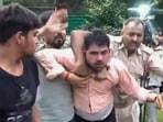 Police personnel detain a man after he allegedly hurled a slipper at Independent MP Pappu Yadav during a press conference, in New Delhi, 