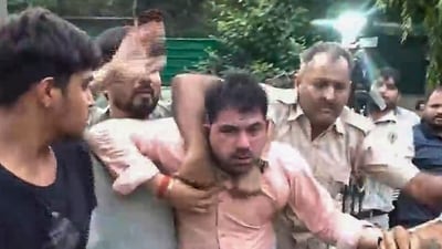 Police personnel detain a man after he allegedly hurled a slipper at Independent MP Pappu Yadav during a press conference, in New Delhi, (PTI) Police personnel detain a man after he allegedly hurled a slipper at Independent MP Pappu Yadav during a press conference, in New Delhi, (PTI)