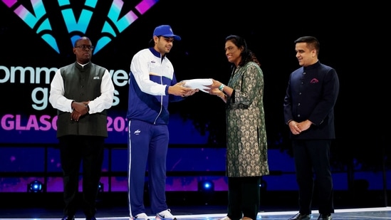 India's Neeraj Chopra, President of the Indian Olympic Association PT Usha and Gujarat deputy chief minister Harsh Sanghavi receive the flag during the closing ceremony
