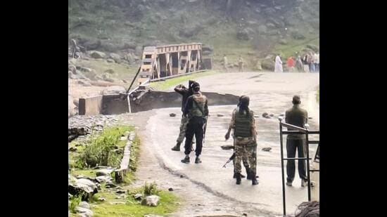 Security personnel stand guard near a damaged bridge after a cloudburst triggered flash floods in the Batkoot area of Pahalgam, in Anantnag district on Monday. (PTI)
