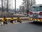 Three members of the Spokane Fire Department sit on a curb in front of burned-out residential homes in the Balboa neighborhood of Spokane, Washington, on August 2, 2026. (Photo by Erick Doxey / AFP)(AFP)