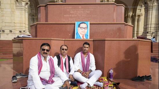Samajwadi Party (SP) MLA Sachin Yadav, right, stages a sit-in outside the Vidhan Sabha after being suspended for the remainder of the session, in Lucknow on Tuesday. (PTI PHOTO)
