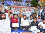 Students hold banners and raise slogans while protesting against the alleged paper leak of the JPSC exam at Jaipal Singh Stadium, in Ranchi on Tuesday.