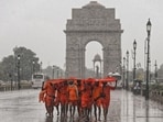Kanwariyas shield themselves from heavy rainfall at India Gate in New Delhi. (PTI)