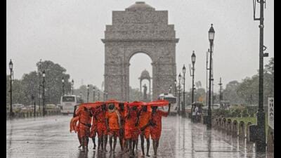 Kanwariyas shield themselves from heavy rainfall at India Gate in New Delhi. (PTI) Kanwariyas shield themselves from heavy rainfall at India Gate in New Delhi. (PTI)