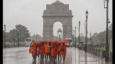 Kanwariyas shield themselves from heavy rainfall at India Gate in New Delhi. (PTI) Kanwariyas shield themselves from heavy rainfall at India Gate in New Delhi. (PTI)