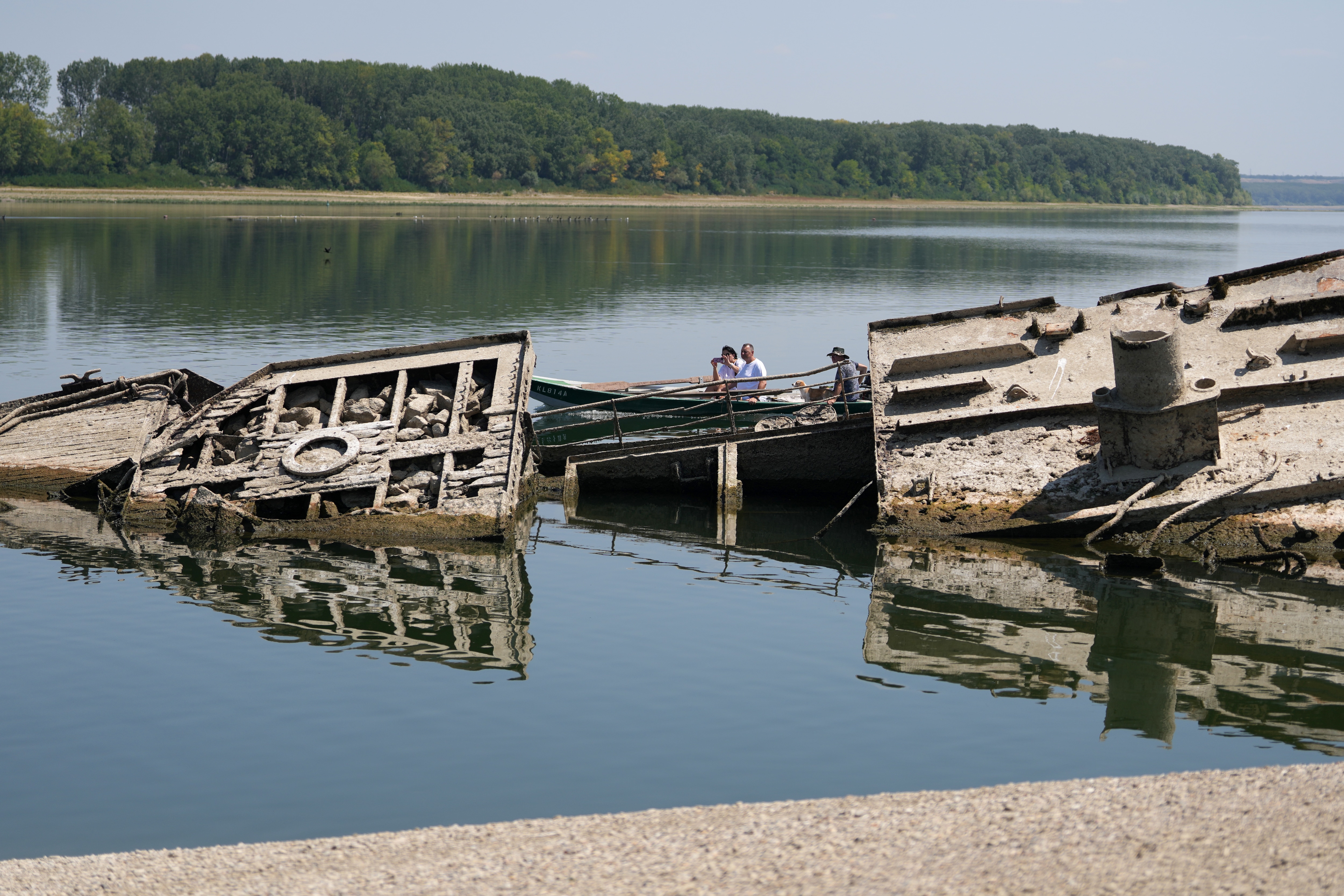 A man walks on the sandbank by the wreckage of a WWII German warship, emerged due to the drought, in front of Djerdap II, a large dam on the Danube River, between Romania and Serbia, near Prahovo, Serbia. A man walks on the sandbank by the wreckage of a WWII German warship, emerged due to the drought, in front of Djerdap II, a large dam on the Danube River, between Romania and Serbia, near Prahovo, Serbia.