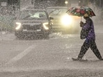 A person crosses a road amid rainfall, in New Delhi. 
