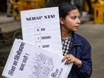 A demonstrator holds placards during a protest against the police crackdown on students and youth over the NEET paper leak issue, at Jantar Mantar.